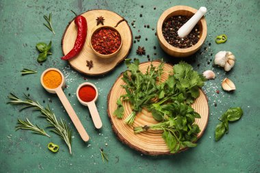 Ahşap yuvarlak dilimler, otlar ve yeşil grunge arka planda baharat kepçeleri, yakın plan