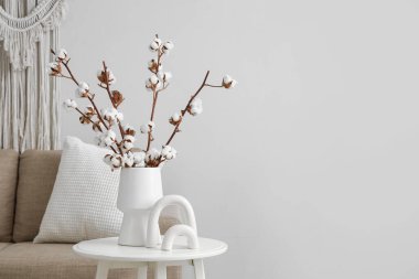 Pamuk çiçekli vazo ve biblo oturma odasındaki beyaz duvarın yanında, yakın plan.