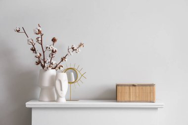 İçinde pamuk çiçekleri olan vazo, heykelcik ve oturma odasındaki çekmecelerin üstündeki kutu, yakın plan.