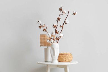 Pamuk çiçekli vazo, hasır kutu ve lamba oturma odasında, yakın plan.