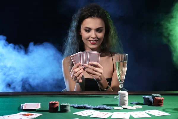 Beautiful woman holding glass of champagne at poker table in casino and  looking away — playing, cheater - Stock Photo | #230985696