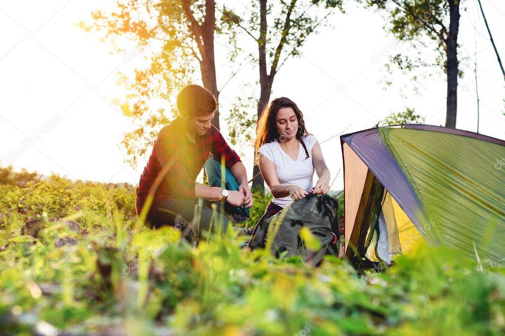 Young couple setting up tent outdoors,hiking and camping.