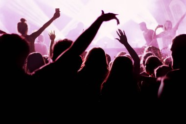 Parlak sahne ışıkları önünde konser kalabalığının siluetleri
