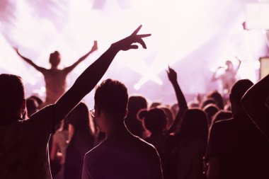 Parlak sahne ışıkları önünde konser kalabalığının siluetleri