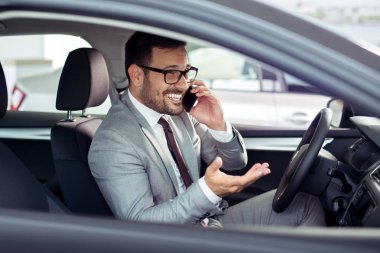 Genç iş adamı arabada telefon ile