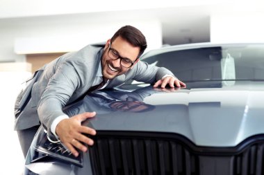 Sevinçle gülümseyen ve yeni bir araba bayilik showroom, kucaklayan bir işadamı portresi