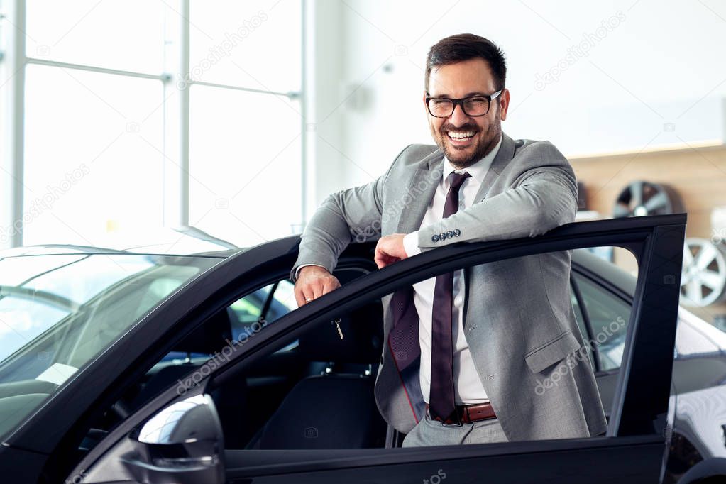 Successful businessman in a car dealership - sale of vehicles to customers