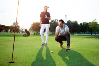 Golf sahasında golf oynayan genç bir çift.