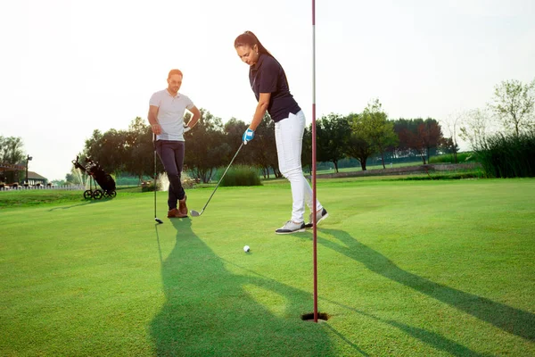 Golf sahasında golf oynayan genç bir çift.