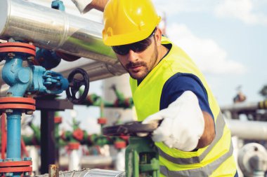 Petrol işçisi petrol platformunda vanayı çeviriyor.