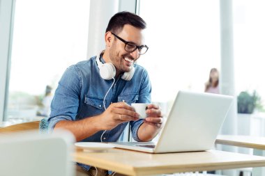 Genç bağımsız kahvehane laptop üzerinde çalışıyor