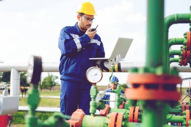 Dizüstü bilgisayar ve bir radyo istasyonunda konuşan petrol pompa üzerinde çalışan bakar