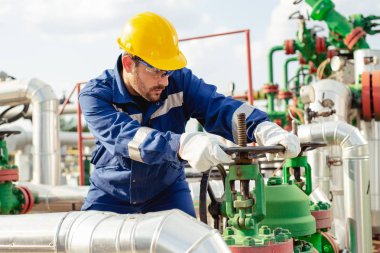 Petrol işçisi petrol platformunda vanayı çeviriyor.