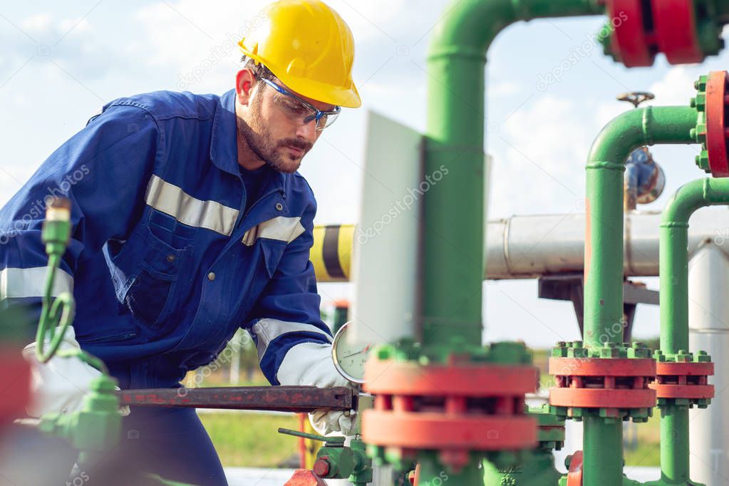Worker adjusting gauge at oil refinery