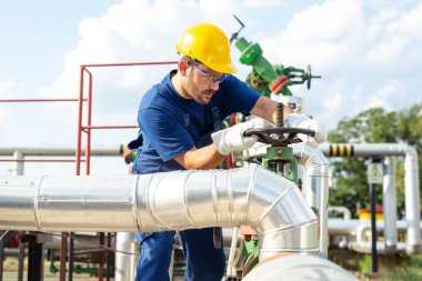 Petrol işçisi petrol platformunda vanayı çeviriyor.