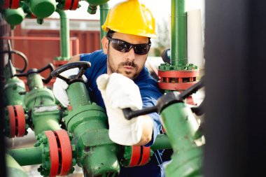 Petrol işçisi petrol platformunda vanayı çeviriyor.