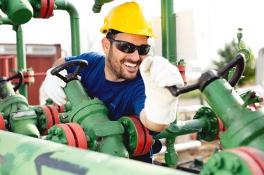 Petrol işçisi petrol platformunda vanayı çeviriyor.