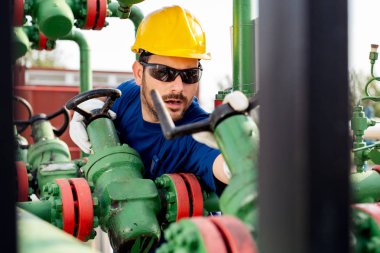 Petrol işçisi petrol platformunda vanayı çeviriyor.
