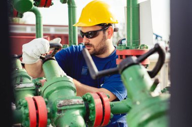Petrol işçisi petrol platformunda vanayı çeviriyor.
