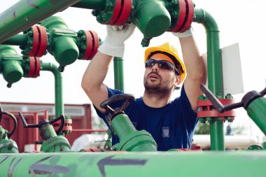 Petrol işçisi petrol platformunda vanayı çeviriyor.