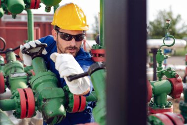 Petrol işçisi petrol platformunda vanayı çeviriyor.