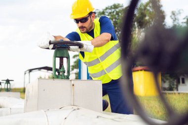 Petrol işçisi petrol boru hattı üzerinde Vana kapatır