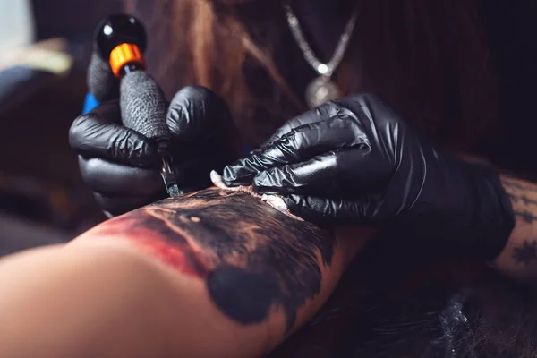 Tattoo artist makes a tattoo on a man\'s hand