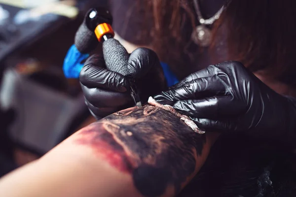 Tattoo artist makes a tattoo on a man\'s hand