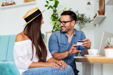 Genç çift ile kredi kartı ve bir kafede dizüstü online satın alma.