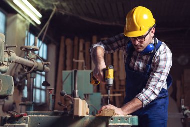 Bir atölye bir sandalye onarmak için matkap kullanan erkek marangoz