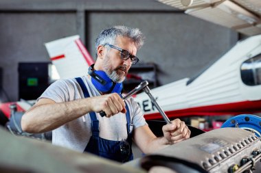 Uçak tamircisi havaalanı hangarında bir uçak motorunu tamir ediyor 