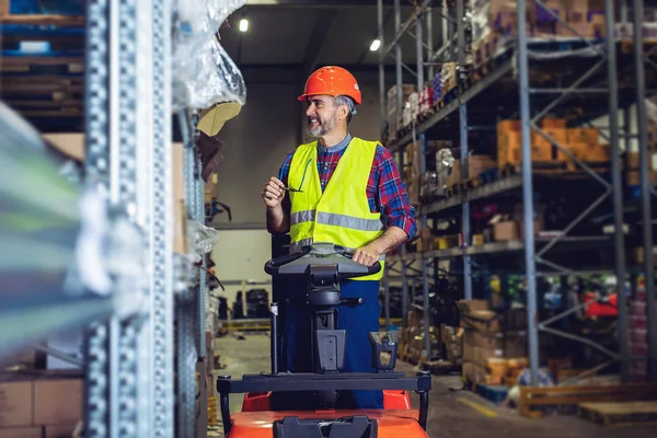 Man or loader on forklift loading cargo at warehouse