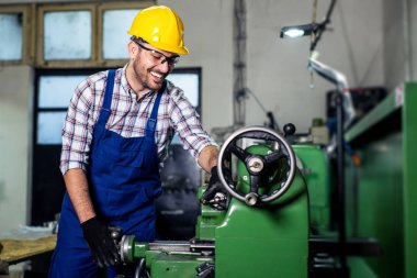 Turner çalışan bir fabrikada bir Torna makinesi üzerinde çalışıyor.