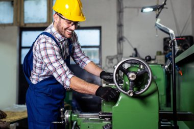 Turner çalışan bir fabrikada bir Torna makinesi üzerinde çalışıyor.