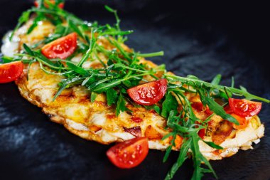 Kahvaltıda ev yapımı yumurtalı omlet. omlet domates ve yeşil taze rucola salatası ile süslenmiş.