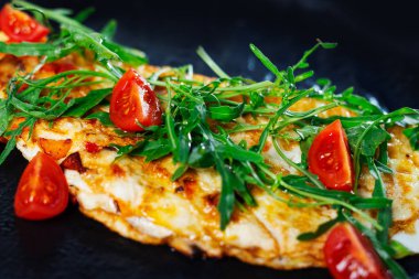 Kahvaltıda ev yapımı yumurtalı omlet. omlet domates ve yeşil taze rucola salatası ile süslenmiş.