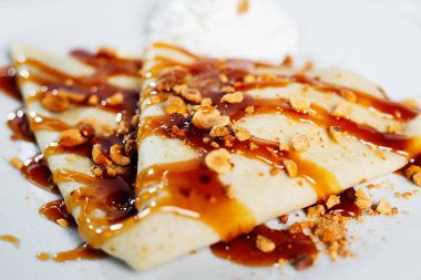 Beyaz arka planda fıstık ve karamel şurubu ile Pancake