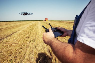 Helikopter arka planda uçarken adam elleriyle uzaktan kumanda tutar. Tarımsal yeni teknolojiler ve yenilikler kavramı