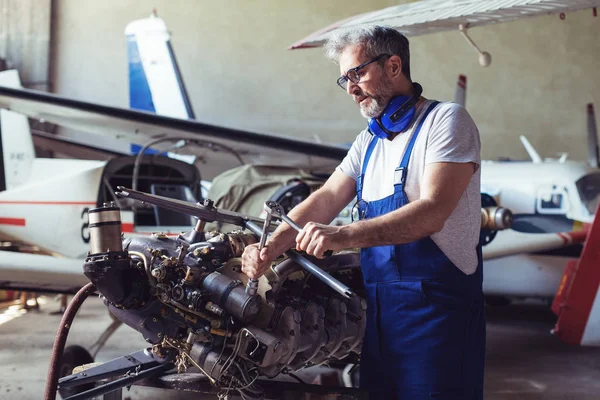 Aircraft maintenance mechanic inspects  plane engine