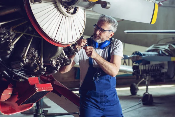 Aircraft mechanic repairs an aircraft engine in an airport hangar