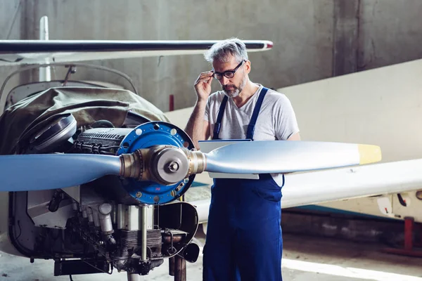 Aircraft maintenance mechanic inspects plane engine