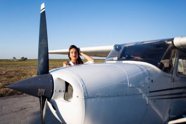 Arka planda modern küçük uçak ile güneş gözlüğü kadın pilot
