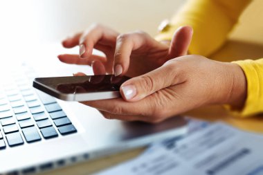Kadın el bir akıllı telefon kullanır ve bir dizüstü bilgisayarda adresinde bulunan İnşaat.