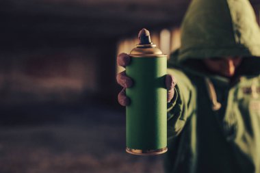 Graffiti sanatçısı spreyi kameraya doğrultuyor.