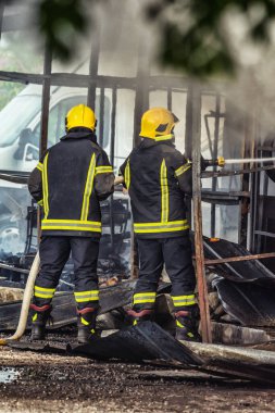 İki itfaiyeci ateş etmek için yüksek basınçlı su püskürtüyor..