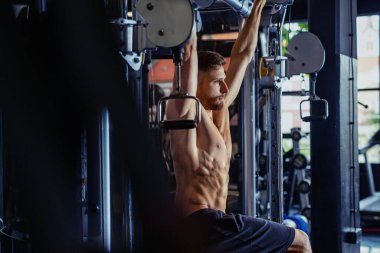 Spor salonunda beden eğitimi alan genç bir vücut geliştirici. Spor salonundaki yakışıklı adam egzersiz yapıyor.. 