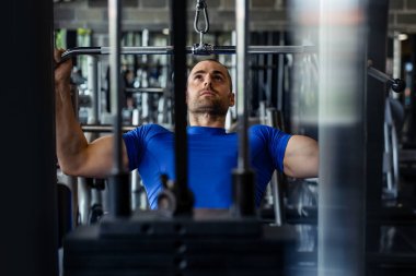 Spor salonunda makine üzerinde egzersiz yapan formda bir adam..