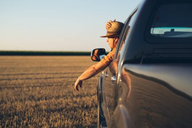 Hasır şapkalı genç adam kamyonet kullanıyor.