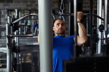 Spor salonunda makine üzerinde egzersiz yapan formda bir adam..