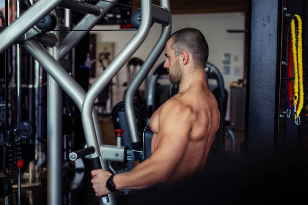 Spor salonunda makine üzerinde egzersiz yapan formda bir adam..